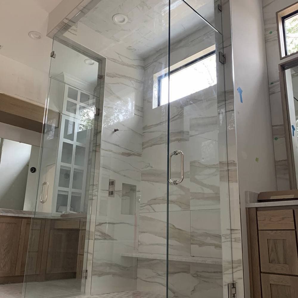 Glass-enclosed walk-in shower finished in large-format marble-look tile