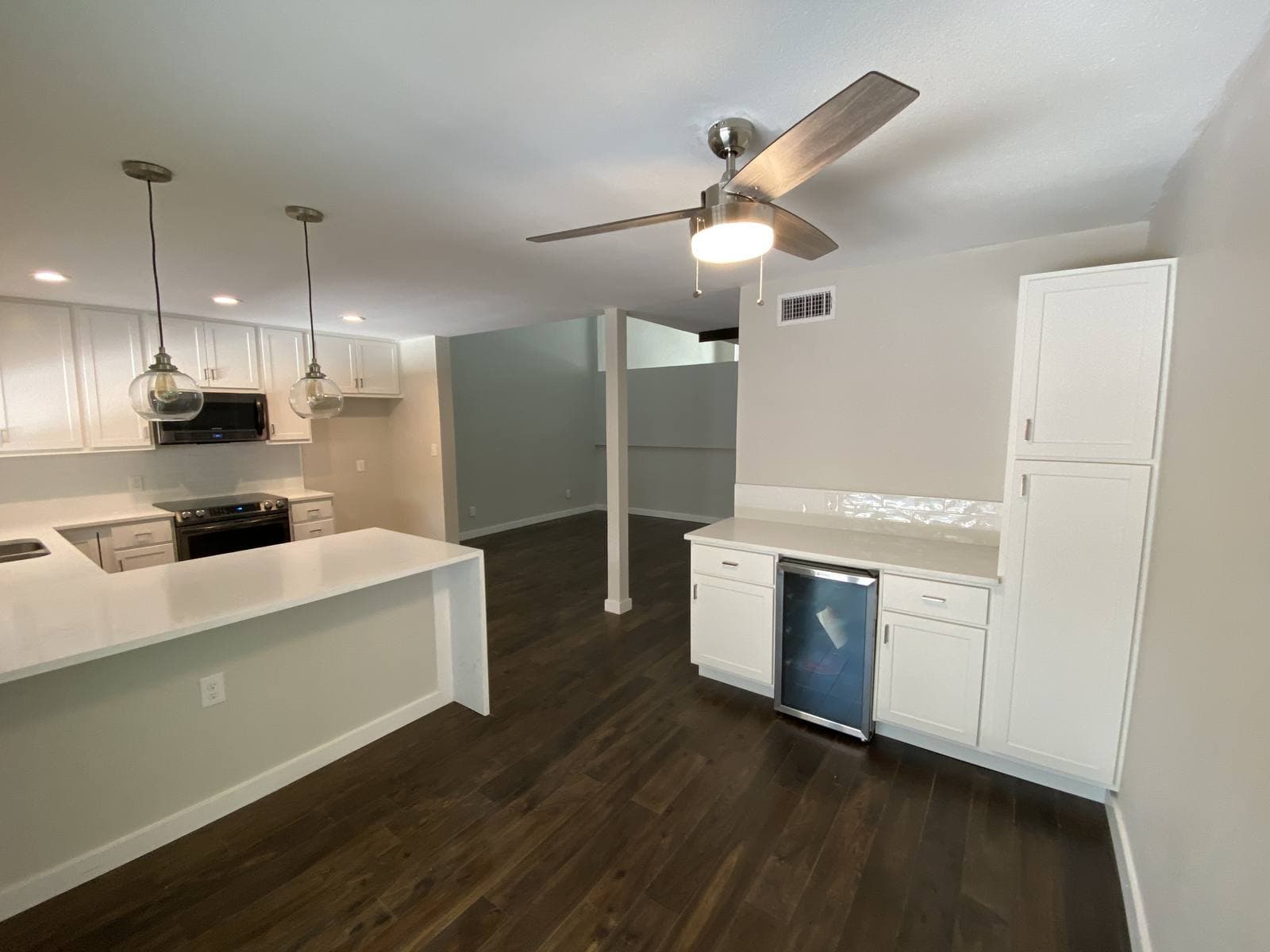 Kitchen with white shaker cabinets, quartz counters, and dark hardwood floors